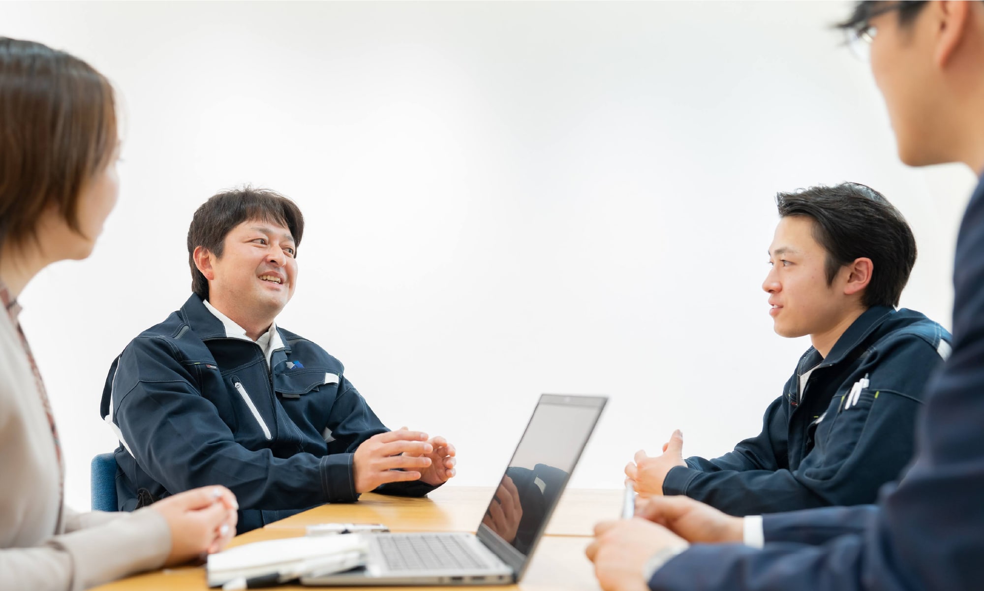 ジェスチャーを交えながら話す先輩社員と真剣に話を聞く若手社員