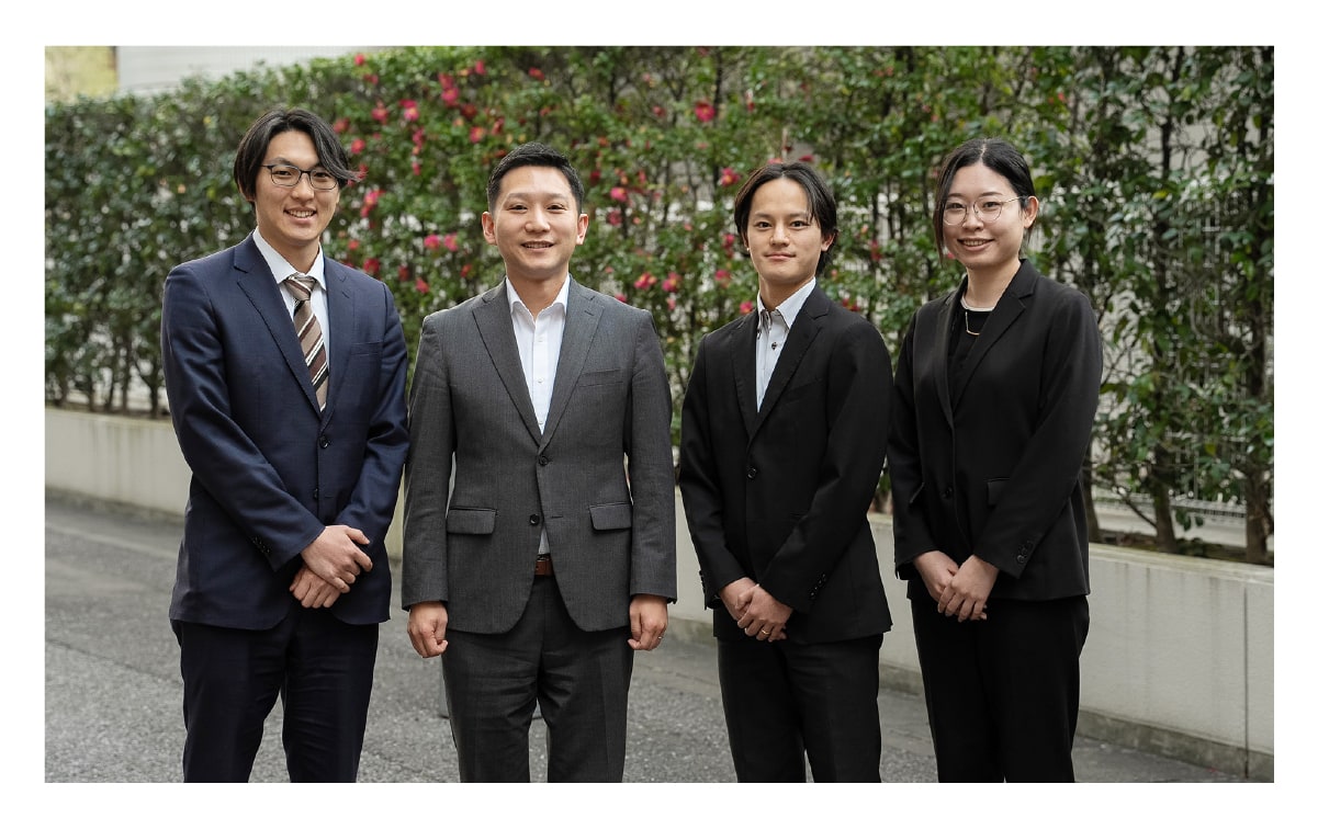先輩社員と3人の若手社員が笑顔で映っている職場の風景